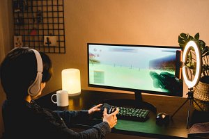 dziewczyna gra na komputerze w grę FPS, nagrywając siebie podczas gry smartfonem