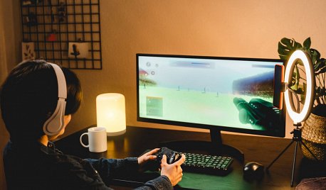 dziewczyna gra na komputerze w grę FPS, nagrywając siebie podczas gry smartfonem