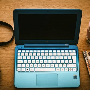 laptop na biurku obok aparatu fotograficznego i telefonu