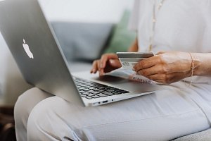 kobieta robiąca zakupy w sklepie internetowym trzymająca kartę płatniczą
