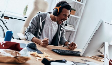 Rozzłoszczony mężczyzna w słuchawkach krzyczy do ekranu komputera